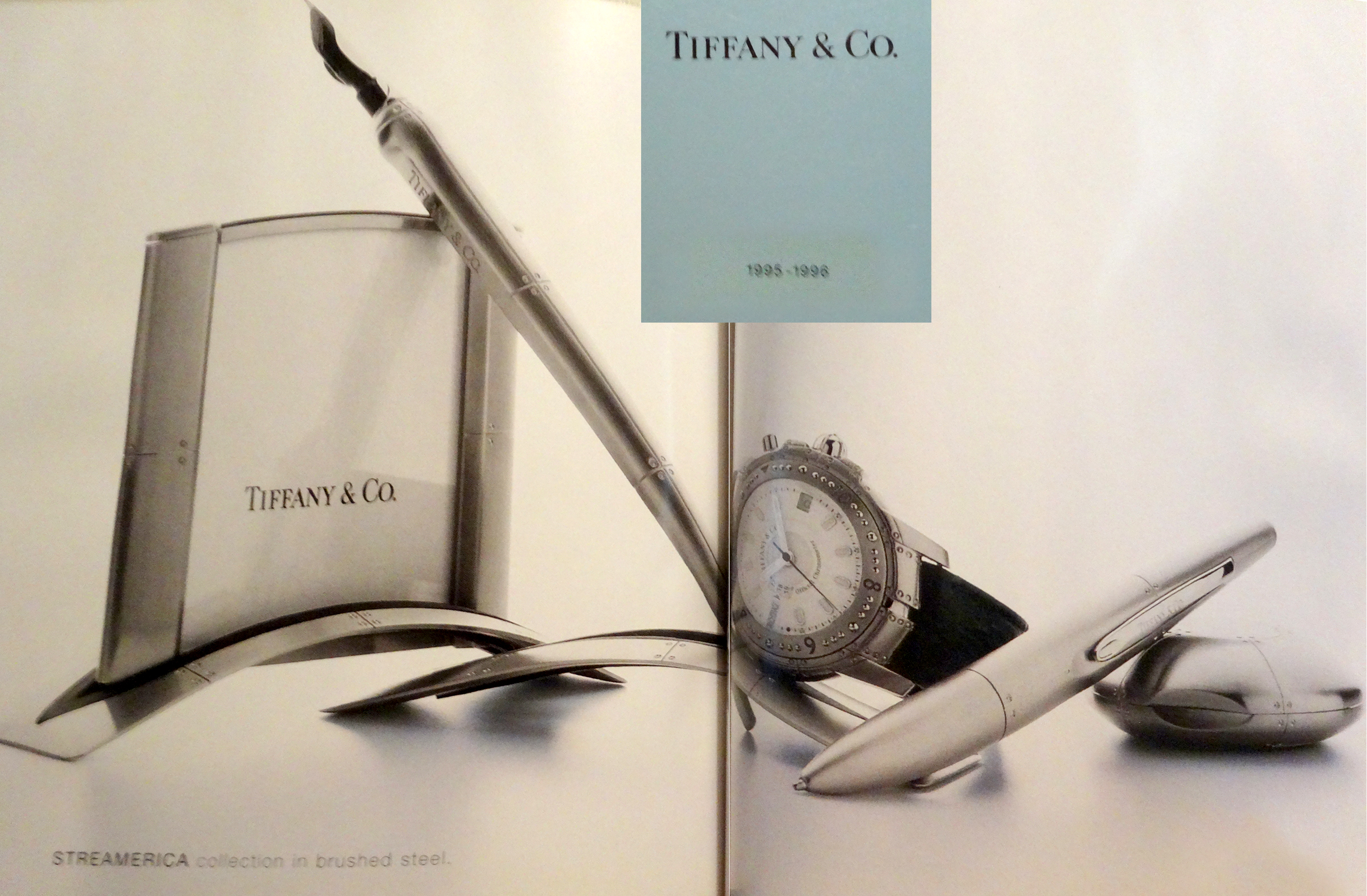 A Page from a 1995 Tiffany & Co. Blue Catalog showcasing Streamerica Stainless Steel Airframe Picture Frame Medium, Airframe dipping ink pen with stand, Automatic Watch with leather band, Ballpoint Pen, and Perisphere Nesting Box.